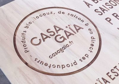 Gravure et découpe laser d'un panneau signalétique stop trottoir en bois pour le restaurant BIO Casa Gaia