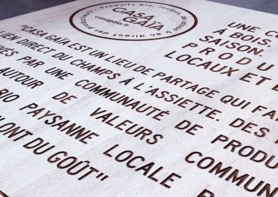 Gravure et découpe laser d'un panneau signalétique stop trottoir en bois pour le restaurant BIO Casa Gaia